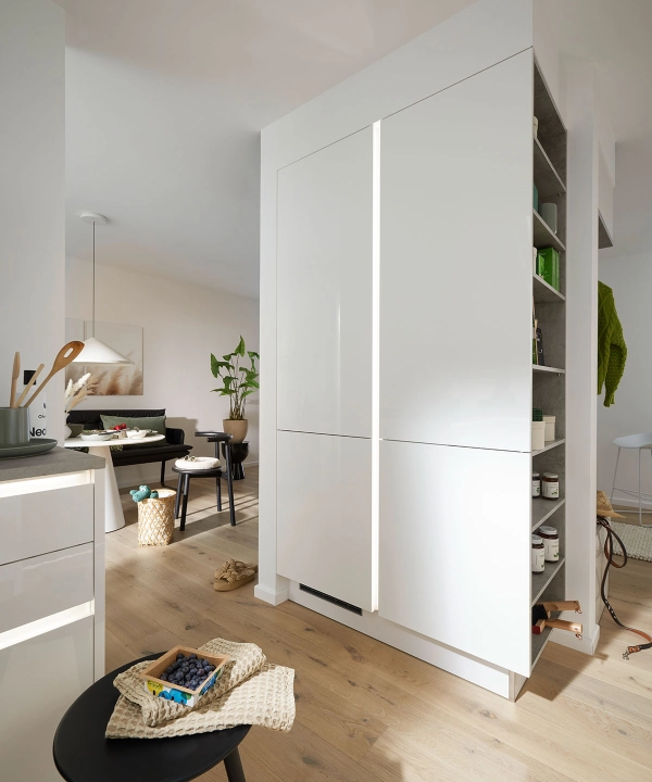 Une cuisine moderne blanche avec parquet et plantes en arrière-plan, Nolte Kitchen.