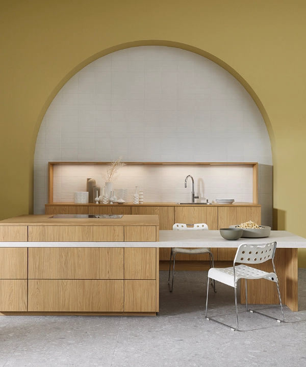 Eine moderne Küche mit Holzfronten und Kochinsel vor einer olivgrünen Wand, Nolte Küchen.