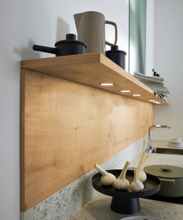 Ein Küchenregal mit Geschirr und Deko, darunter beleuchtete Arbeitsfläche. Nolte Küchen.