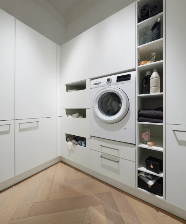 Une buanderie moderne avec machine à laver et étagères, conçue par Nolte Utility Rooms.