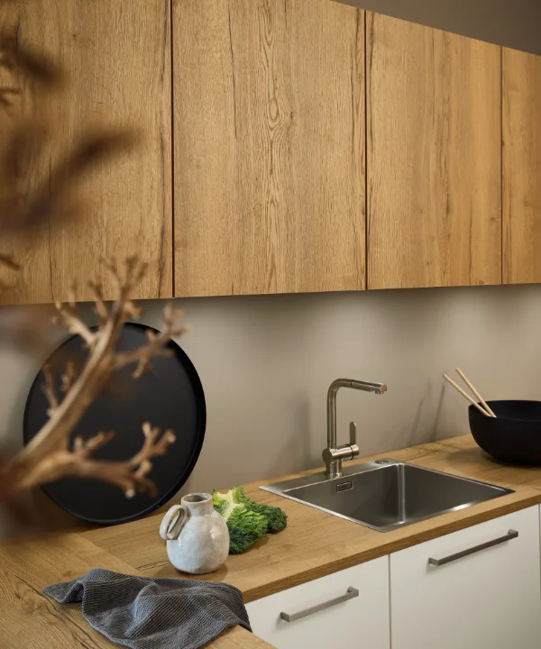Una cocina moderna con toques de madera y fregadero de acero inoxidable, diseñada por Nolte Cocina.