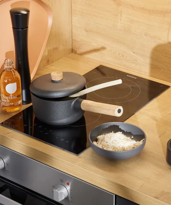 Dans une cuisine moderne avec des détails en bois, une cuisinière avec une casserole et un bol de riz. Nolte Kitchen.