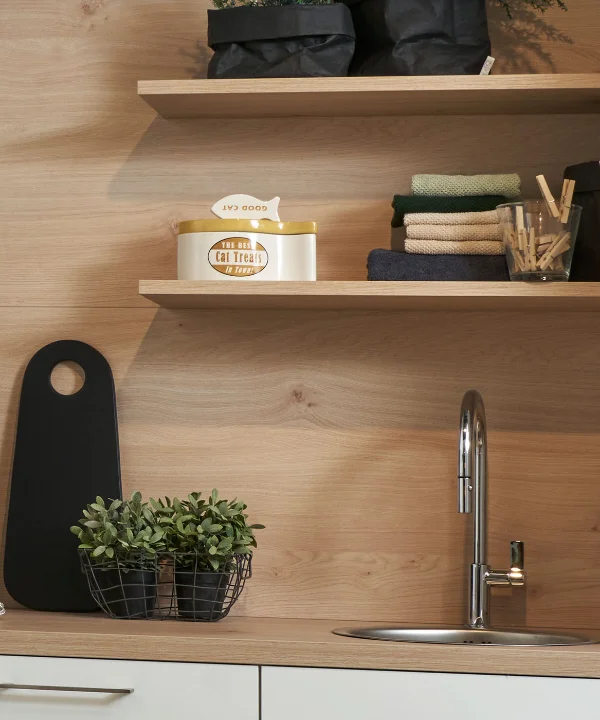 Une cuisine moderne avec étagères en bois et évier, décorée de plantes et accessoires. Nolte Kitchen.
